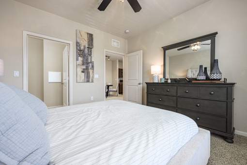 A bedroom with a large bed, a dresser, and a mirror.
