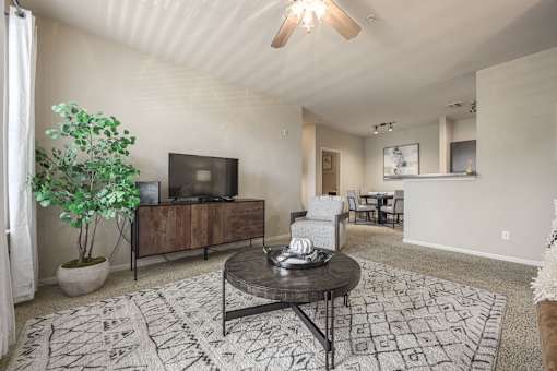A living room with a black coffee table and a tv on a cabinet.