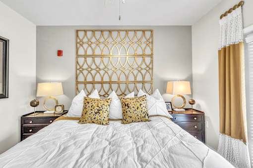A bedroom with a large bed and two lamps on either side.