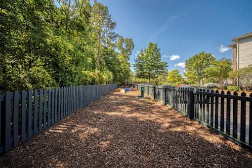 A long, narrow pathway flanked by trees and fences.