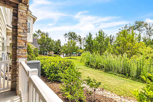 A house with a balcony overlooks a lush green yard.