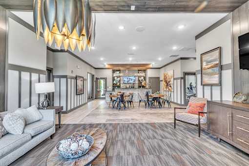 A modern living room with a grey sofa, wooden coffee table, and a large chandelier.