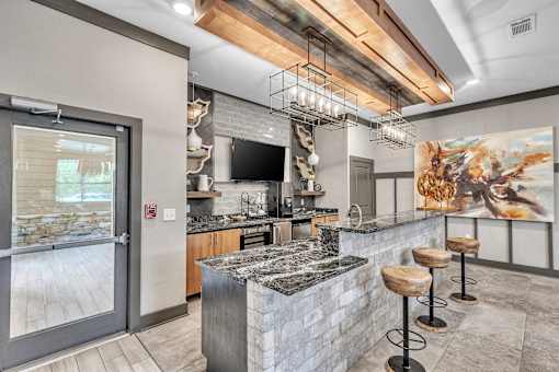 A modern kitchen with a stone counter and a bar area.