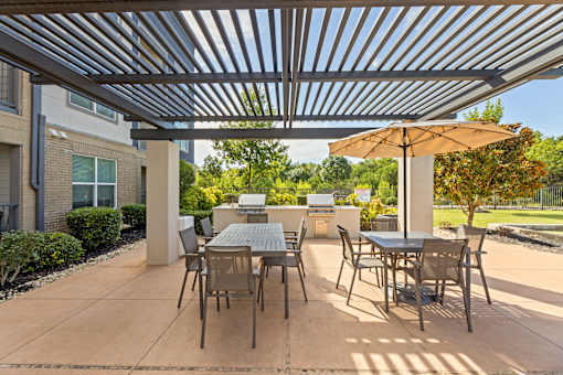 A patio with a table and chairs under a metal roof.