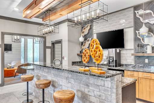 A modern kitchen with a stone counter and a TV mounted on the wall.
