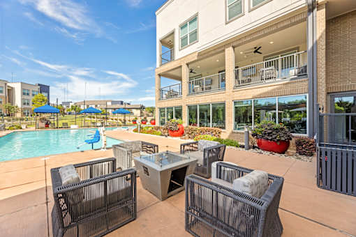 A patio with a table and chairs overlooking a pool.