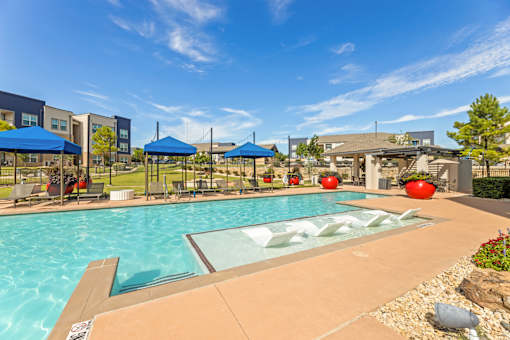 A swimming pool with a glass divider in the middle and a blue umbrella on the left.