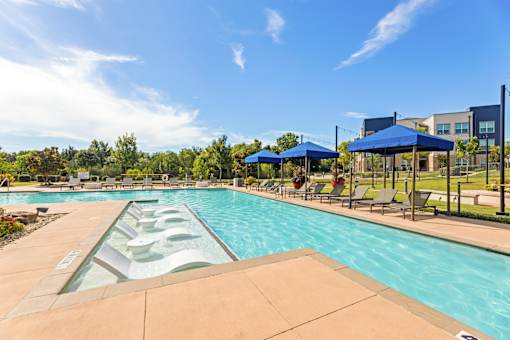A large outdoor swimming pool with a slide and sunshades.