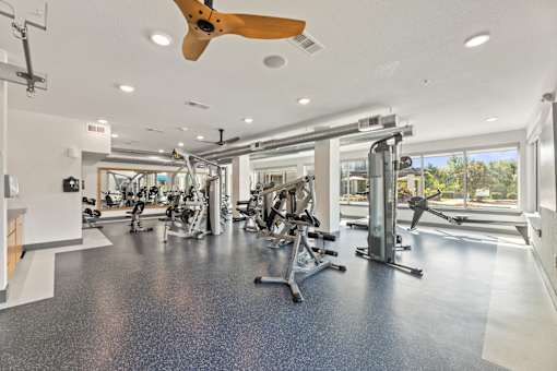 A spacious gym with a variety of equipment and a ceiling fan.