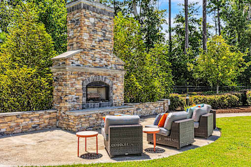 A stone fireplace is surrounded by outdoor furniture.