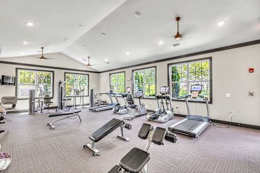 A spacious gym with a variety of equipment and a ceiling fan.