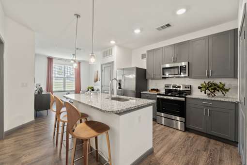 A modern kitchen with wooden chairs and stainless steel appliances.