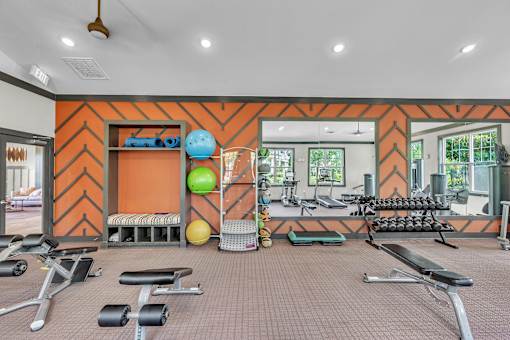 A gym with orange walls and a variety of equipment.
