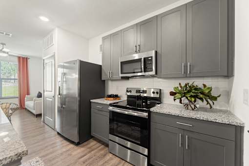 A kitchen with a refrigerator, oven, and microwave.