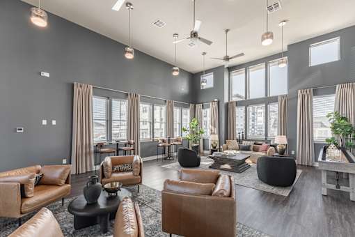 A spacious living room with brown leather furniture and large windows at Prosper Madison Oaks, Madison, AL