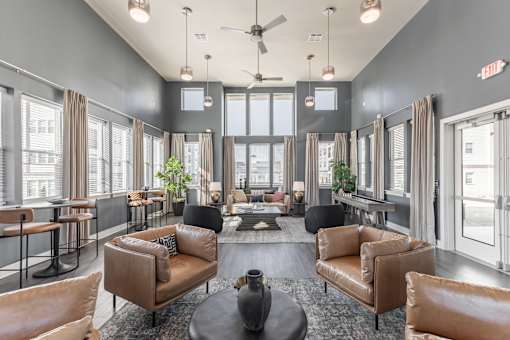 A large, modern living room with brown leather furniture and a glass door leading to a balcony at Prosper Madison Oaks, Madison, AL