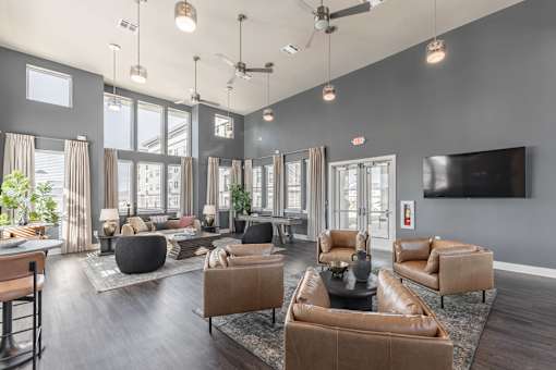 A modern living room with brown leather furniture and a flat screen TV mounted on the wall at Prosper Madison Oaks, Madison, AL