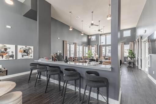 A modern kitchen with a bar area and grey chairs at Prosper Madison Oaks, Madison, AL