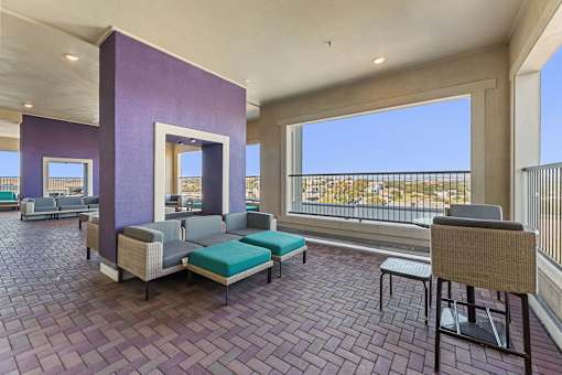 A balcony with a table and chairs overlooking a cityscape.