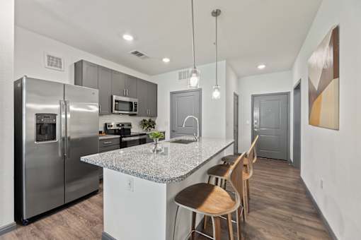 A kitchen with a granite countertop and stainless steel appliances.