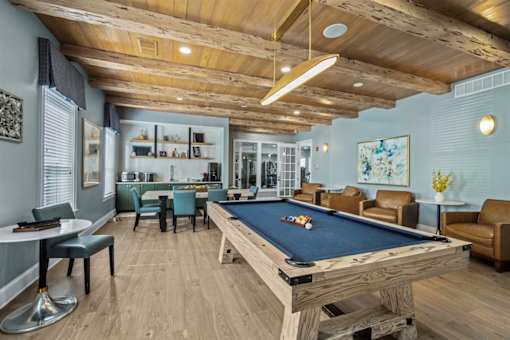 A pool table is in the middle of a room with a wooden floor and ceiling.