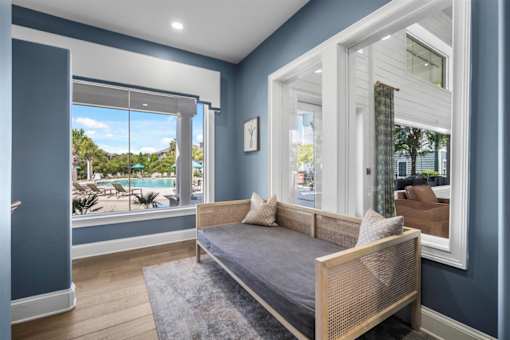A bedroom with a bed, a window with a view of the pool and trees, and a picture on the wall.