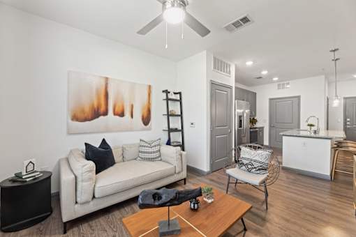 A living room with a white couch and a painting on the wall.