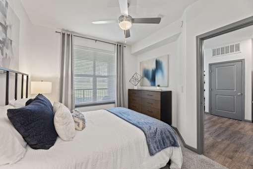 A bedroom with a bed, dresser, and a ceiling fan.