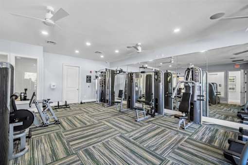 A gym with a variety of equipment including treadmills, weights, and exercise machines.