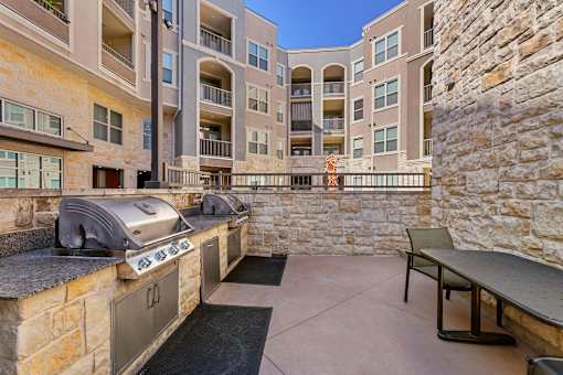 A stone wall separates a patio from a building.