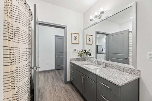 A bathroom with a sink, mirror, and a shower curtain.