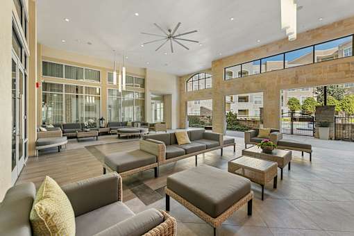 A large, modern living room with a high ceiling and a central chandelier.