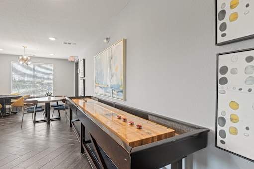 A shiny wooden pool table in a room with a painting on the wall.