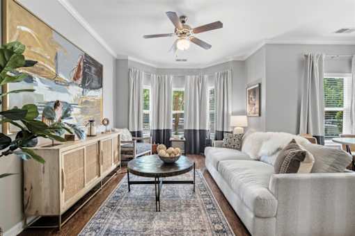 A living room with a large painting on the wall and a ceiling fan.