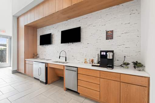 A kitchen with a white brick wall and wooden cabinets.