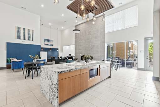 A modern kitchen with a marble island and pendant lights.
