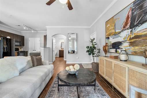 A living room with a grey couch, a black coffee table, and a painting on the wall.