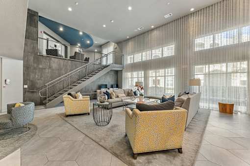 A modern living room with a staircase and a large window.