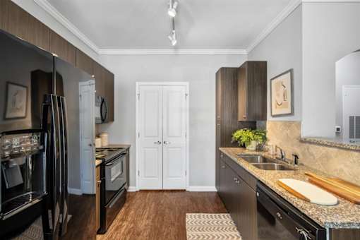 A kitchen with a black fridge and wooden floors.