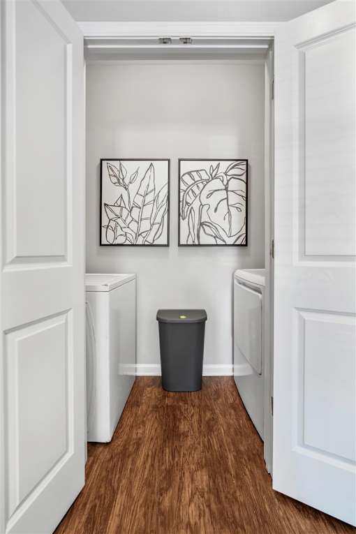 A hallway with a trash can and two framed pictures on the wall.