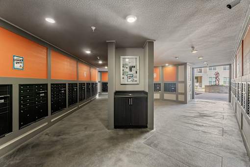A long hallway with orange walls and a black trash can.