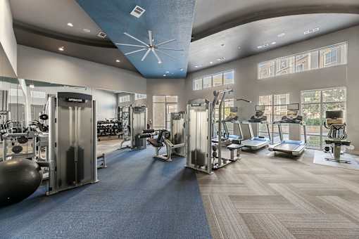 A gym with a variety of equipment including treadmills, weights, and exercise machines.