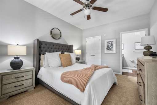 A bedroom with a bed, nightstands, and a ceiling fan.