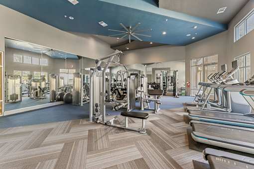 A gym with a variety of equipment including treadmills, weights, and exercise machines.