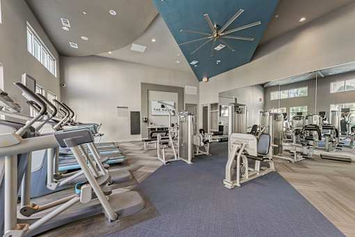 A gym with a variety of equipment including treadmills, weights, and exercise machines.