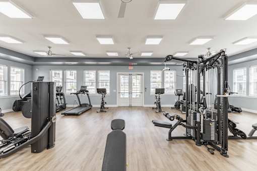 A spacious gym with a variety of equipment and a large mirror on the wall at Prosper Madison Oaks, Madison, AL