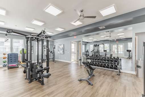 A spacious gym with a variety of equipment including treadmills, weights, and a bench press at Prosper Madison Oaks, Madison, AL