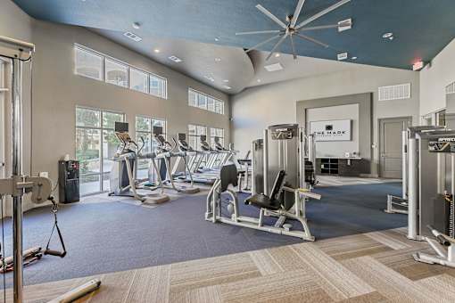 A gym with a variety of equipment including treadmills, weights, and exercise machines.