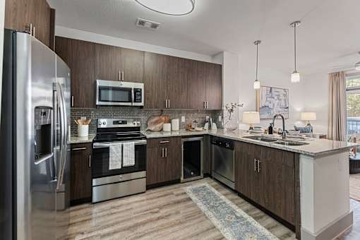 A modern kitchen with a refrigerator, oven, microwave, and sink.
