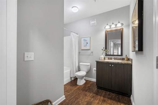 A bathroom with a toilet, sink, and mirror.